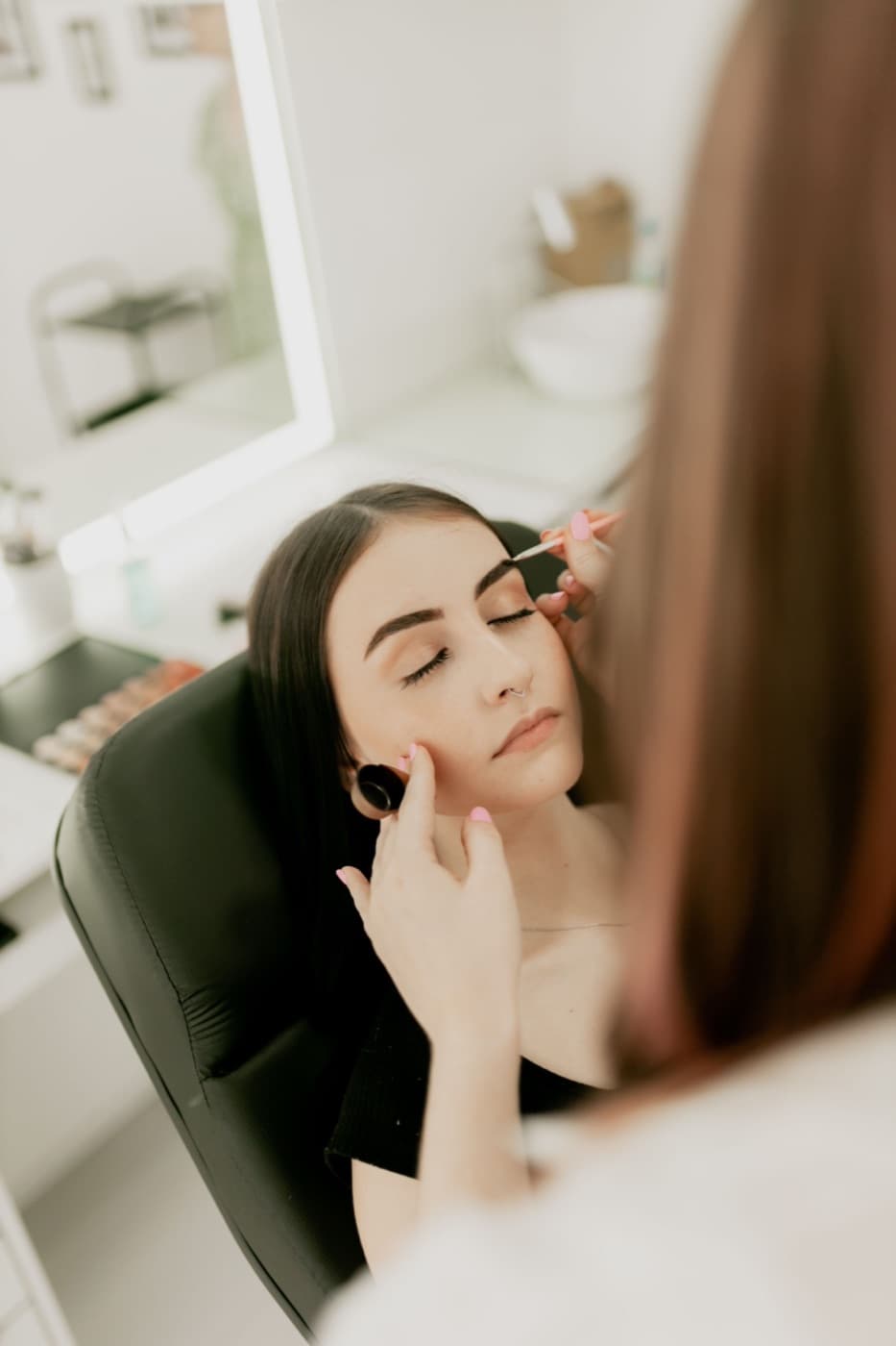 Een visagiste brengt make-up aan bij een klant in een lichte salon